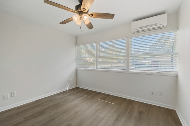 empty room featuring ceiling fan, baseboards, wood finished floors, and a wall unit AC