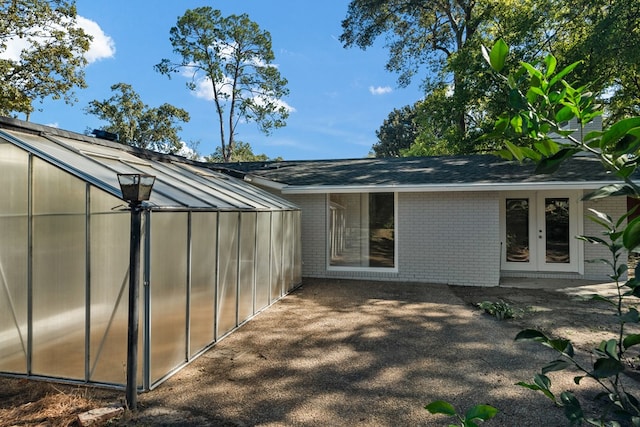 back of house featuring brick siding, an exterior structure, french doors, and an outdoor structure