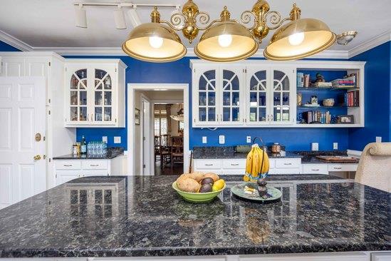 219 Broken Rock Rd, Hamilton, GA 31811 - kitchen with ornamental molding, glass insert cabinets, white cabinetry, dark stone counters, and a large island