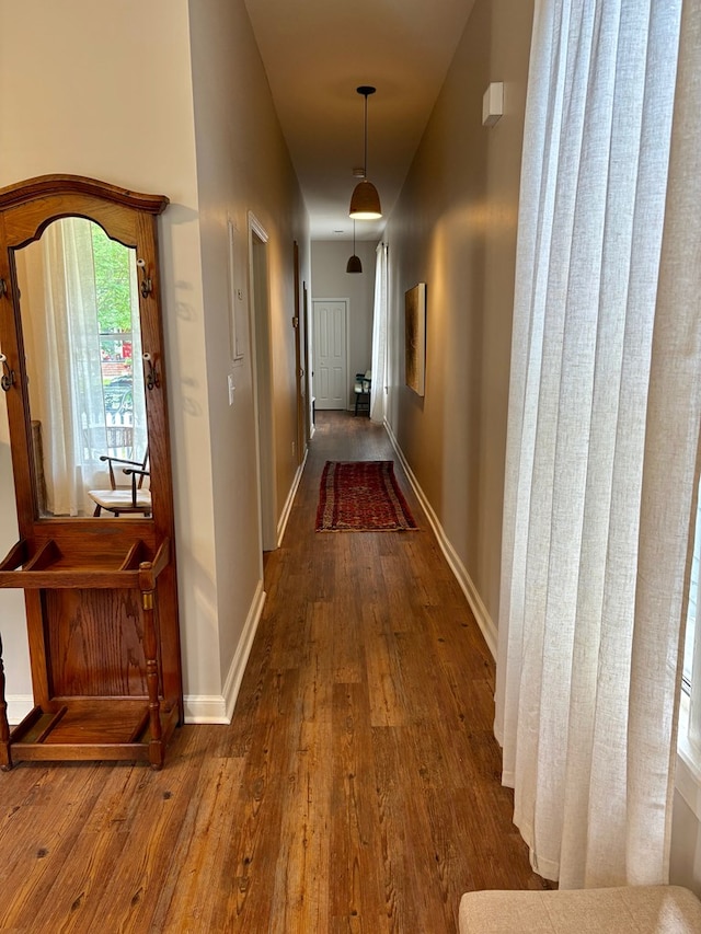 hallway featuring wood finished floors and baseboards