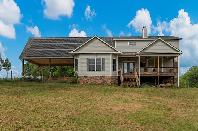 rear view of property with ceiling fan, a chimney, solar panels, french doors, and a lawn