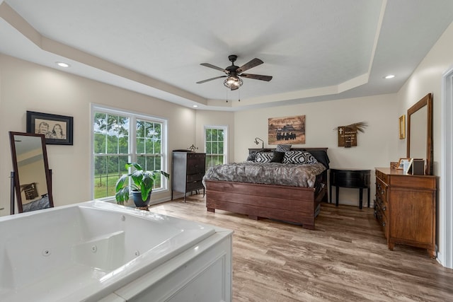 bedroom with recessed lighting, light wood-style flooring, ceiling fan, and a tray ceiling