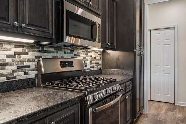 kitchen with light wood-style floors, appliances with stainless steel finishes, backsplash, and dark countertops