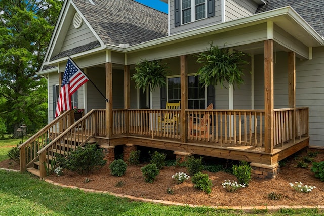 rear view of property featuring a porch and roof with shingles