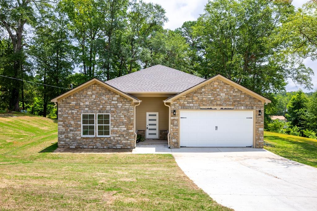2900 23rd Ave, Phenix City, AL 36867 - view of front facade with stone siding, an attached garage, a front yard, and driveway