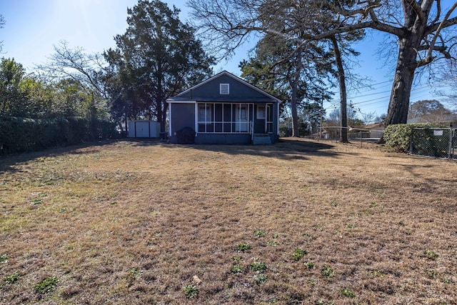 back of property with a shed, a lawn, and a sunroom