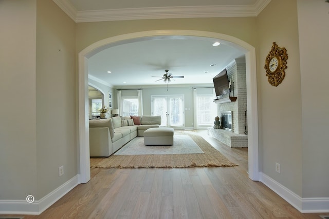 unfurnished living room with ceiling fan, crown molding, light hardwood / wood-style floors, and a brick fireplace