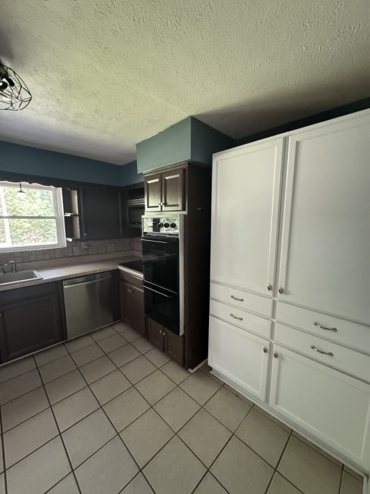 kitchen with sink, stainless steel dishwasher, backsplash, a textured ceiling, and light tile patterned flooring