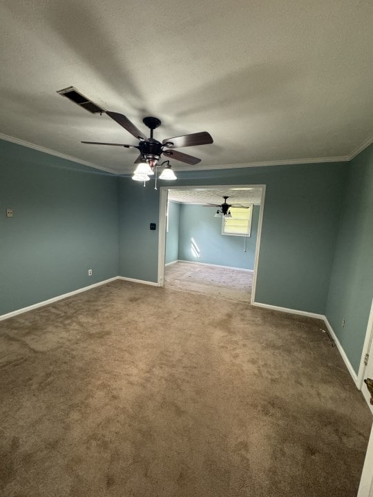 spare room featuring crown molding, carpet, a textured ceiling, and ceiling fan