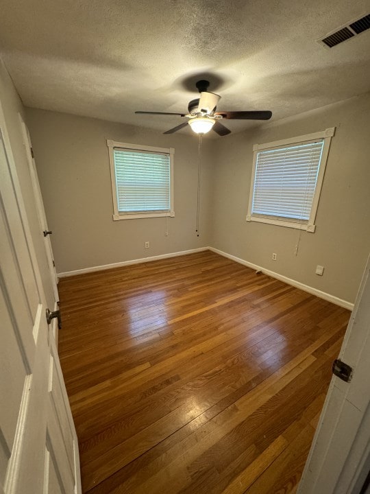 unfurnished bedroom with ceiling fan, a textured ceiling, and hardwood / wood-style flooring