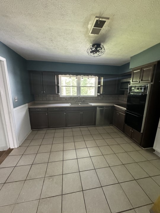 kitchen featuring decorative backsplash, appliances with stainless steel finishes, dark brown cabinets, a textured ceiling, and sink