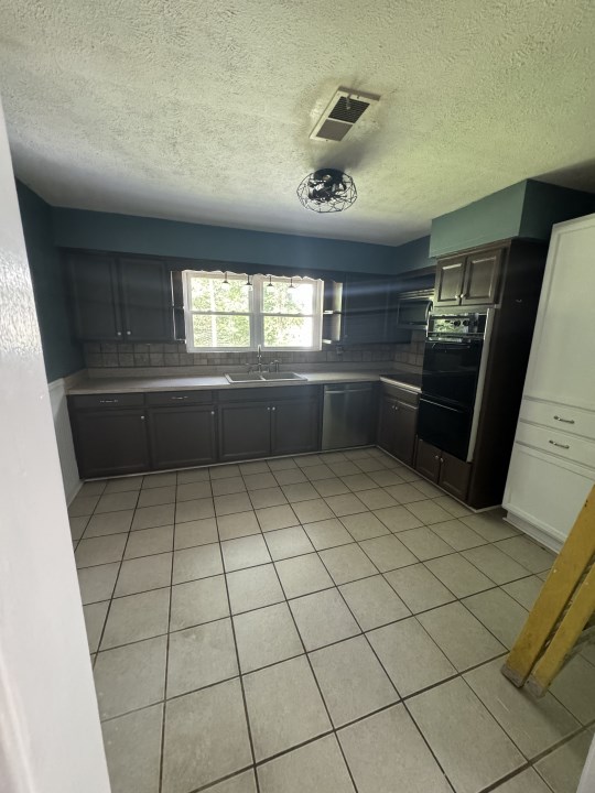 kitchen with tasteful backsplash, sink, light tile patterned flooring, and appliances with stainless steel finishes