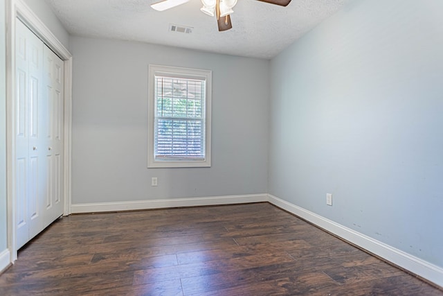 unfurnished bedroom with baseboards, visible vents, dark wood-type flooring, a textured ceiling, and a closet