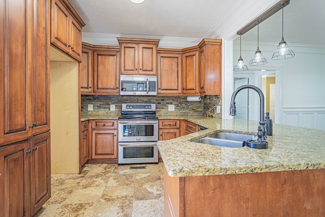 kitchen with a peninsula, appliances with stainless steel finishes, brown cabinets, and a sink