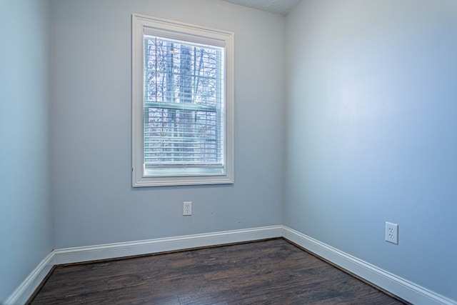 spare room with baseboards and dark wood-style floors