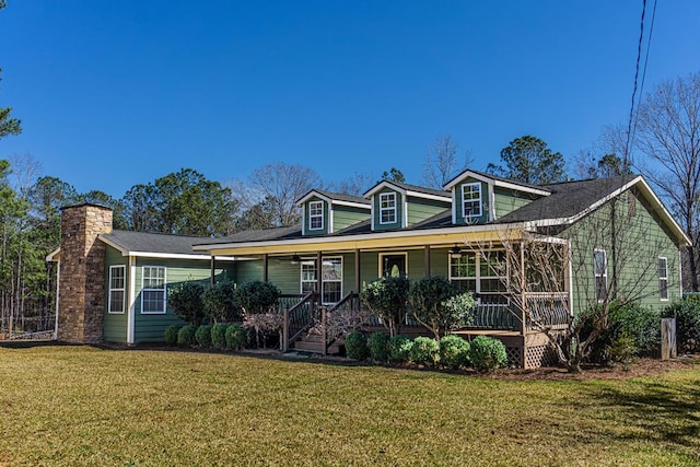 view of front of house with covered porch, a chimney, and a front yard