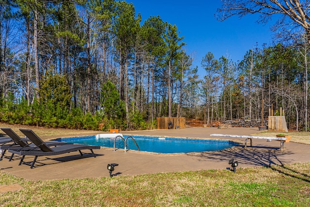 outdoor pool with fence, a diving board, and a patio