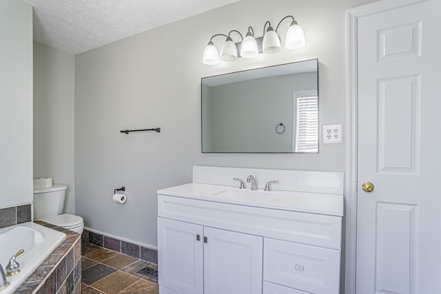 bathroom featuring vanity, baseboards, stone tile flooring, a textured ceiling, and toilet