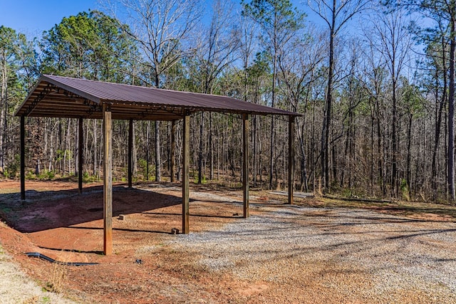 view of yard featuring dirt driveway and a carport