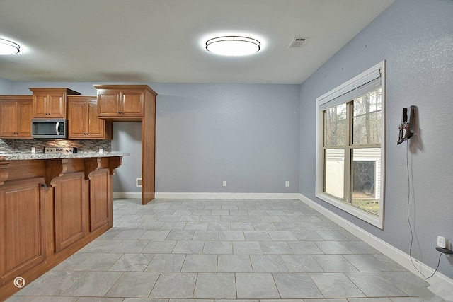 kitchen featuring a healthy amount of sunlight, tasteful backsplash, and a breakfast bar area