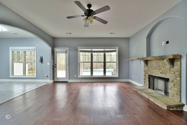 unfurnished living room featuring a stone fireplace, ceiling fan, and hardwood / wood-style flooring