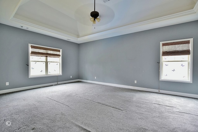 carpeted empty room featuring a raised ceiling, ceiling fan, and crown molding