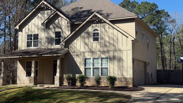 view of front of house with driveway, an attached garage, a front lawn, and board and batten siding