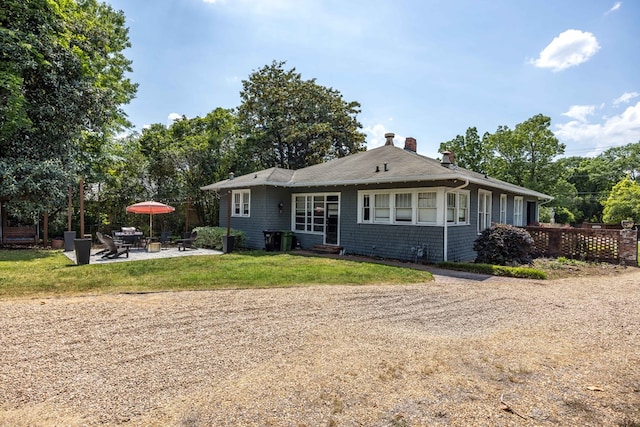 back of house featuring a patio area, fence, a yard, and a chimney