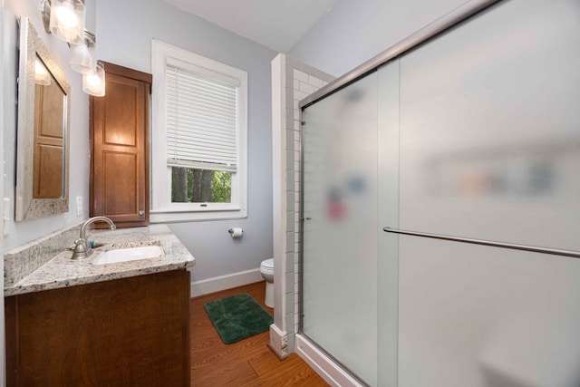 full bathroom featuring vanity, toilet, baseboards, a shower stall, and wood finished floors