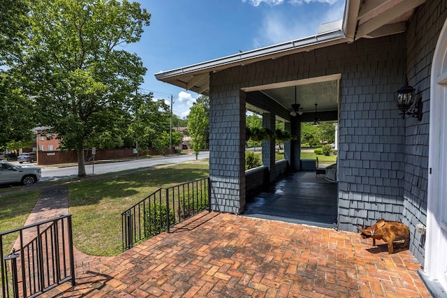 wooden terrace with a porch, ceiling fan, and a yard