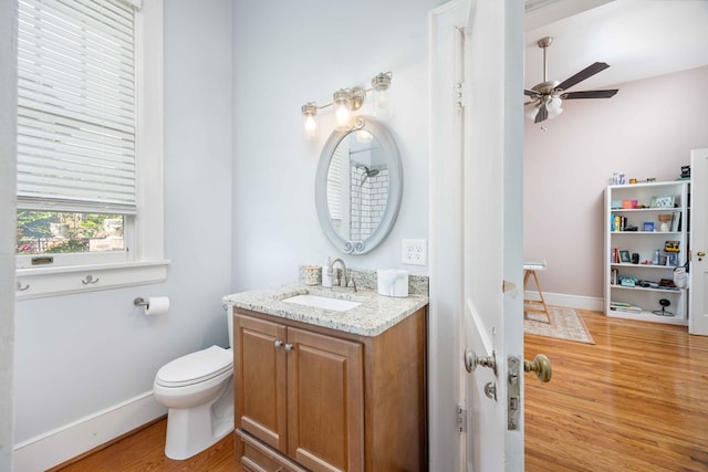 bathroom with a ceiling fan, wood finished floors, vanity, baseboards, and toilet