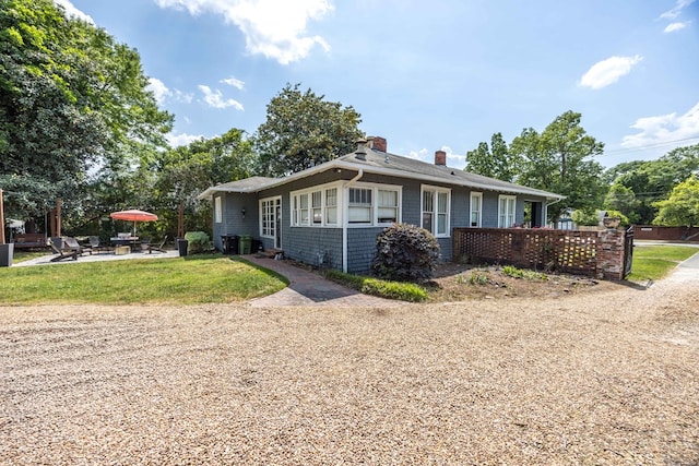 view of front of home featuring a patio area, a front yard, and a chimney