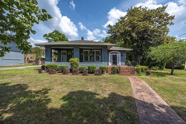 view of front of home featuring a chimney, a porch, and a front lawn