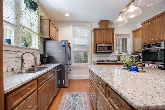 kitchen featuring a sink, light wood-style flooring, appliances with stainless steel finishes, and backsplash