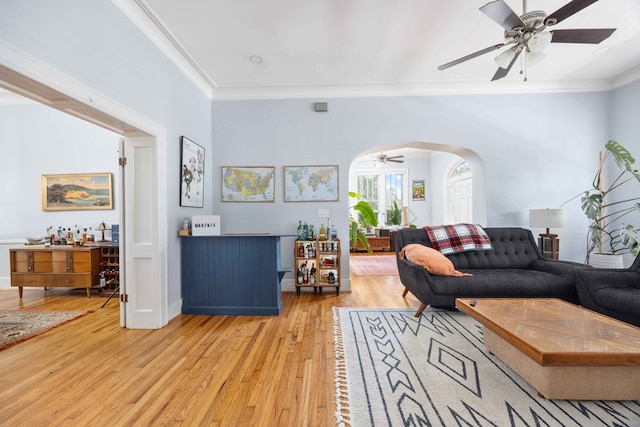 living room with ceiling fan, ornamental molding, and light wood finished floors