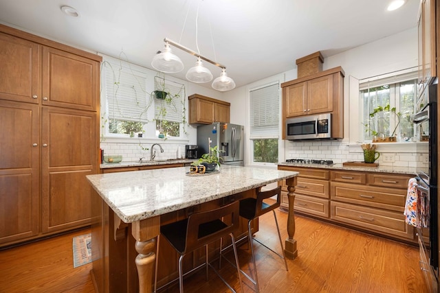 kitchen with brown cabinets, backsplash, appliances with stainless steel finishes, and a sink