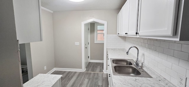 3315 Urban Ave, Columbus, GA 31907 - kitchen with wood finished floors, white cabinets, decorative backsplash, arched walkways, and a textured ceiling