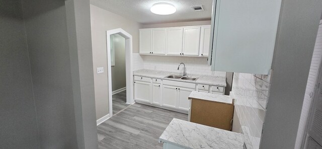 3315 Urban Ave, Columbus, GA 31907 - kitchen with backsplash, white cabinetry, light wood-style flooring, light countertops, and arched walkways