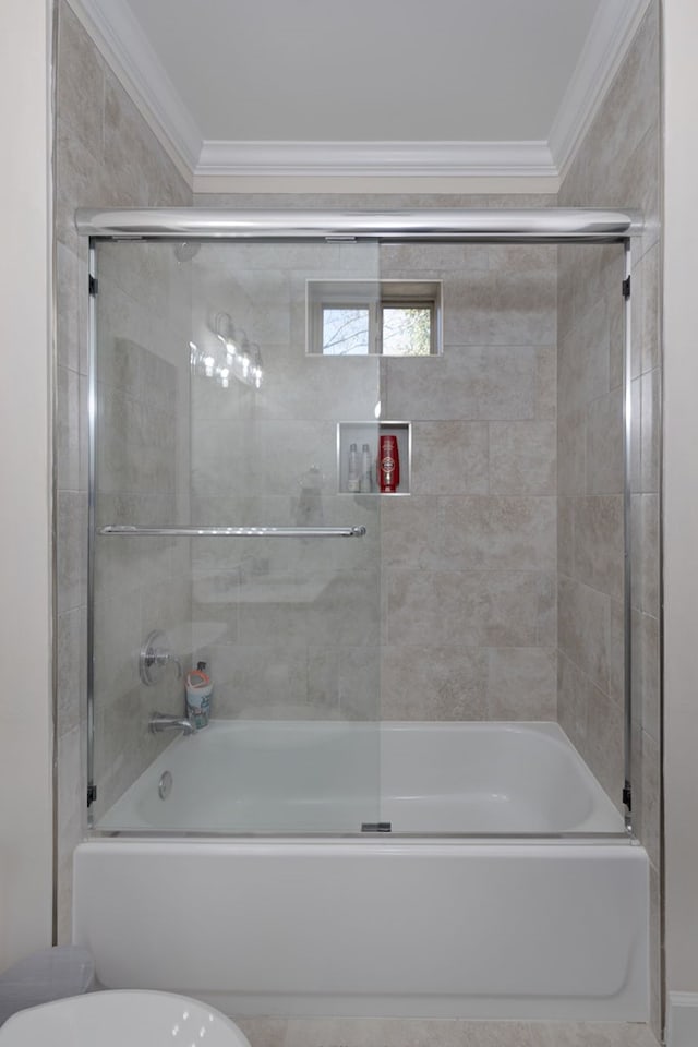 bathroom featuring toilet, combined bath / shower with glass door, and ornamental molding