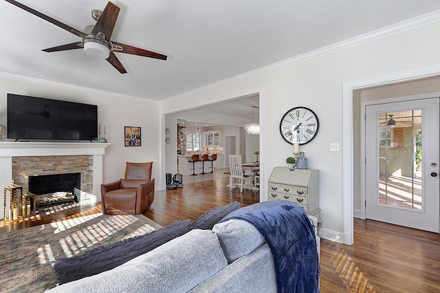 living room with ceiling fan, a fireplace, wood-type flooring, and ornamental molding