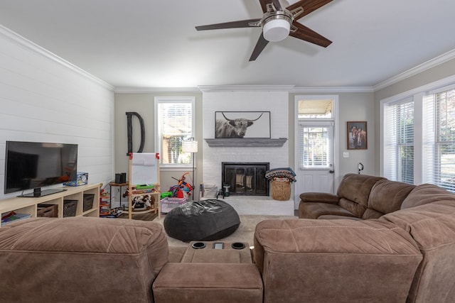 carpeted living room featuring ceiling fan, crown molding, and a brick fireplace