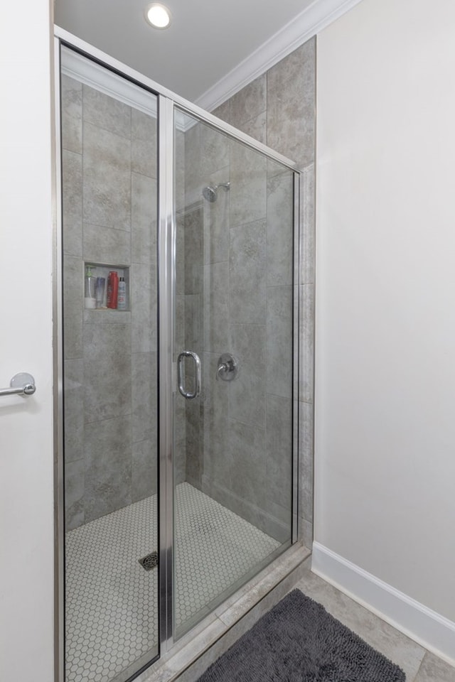 bathroom featuring tile patterned floors, a shower with door, and crown molding