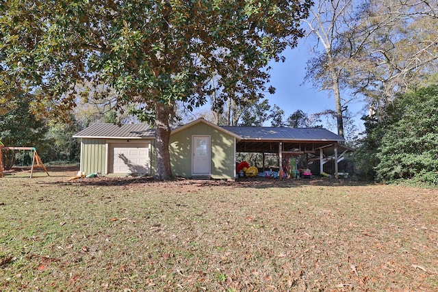 back of house with an outbuilding, a carport, a yard, a playground, and a garage