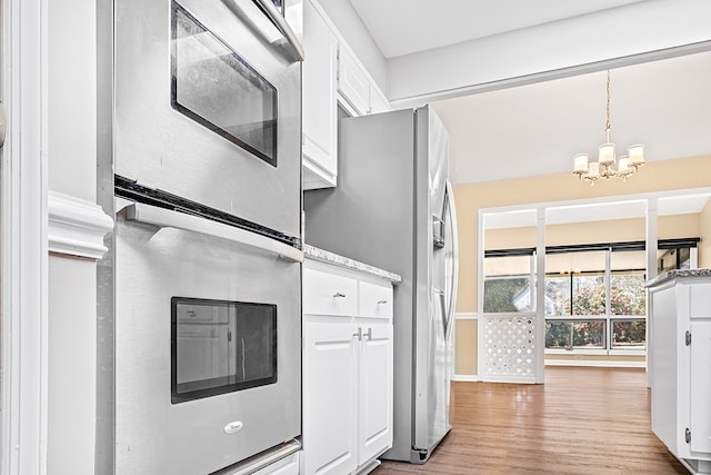 kitchen featuring oven, white cabinetry, light wood-style floors, stainless steel fridge with ice dispenser, and pendant lighting