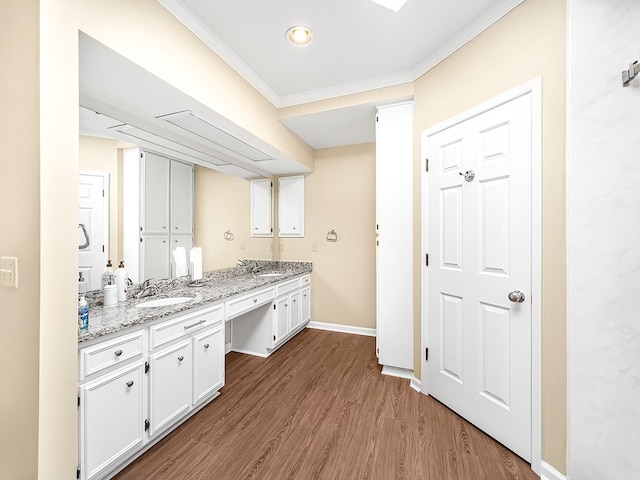 bathroom with ornamental molding, double vanity, a sink, and wood finished floors