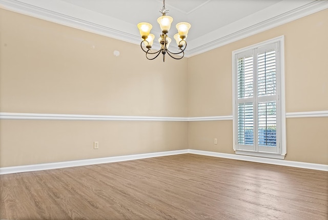 unfurnished room with a chandelier, ornamental molding, wood finished floors, and baseboards