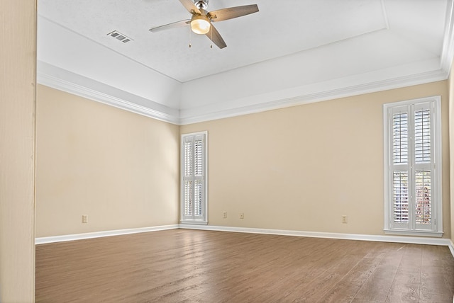 empty room featuring ceiling fan, wood finished floors, visible vents, and baseboards