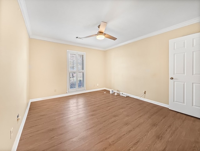 empty room featuring ceiling fan, crown molding, baseboards, and wood finished floors