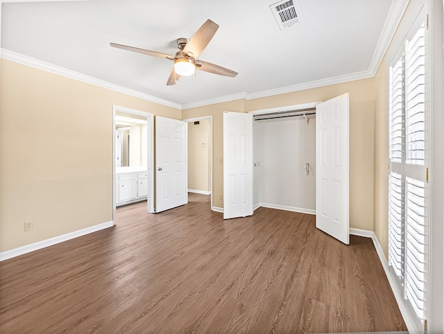 unfurnished bedroom featuring ornamental molding, visible vents, baseboards, and wood finished floors