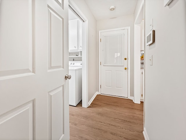 corridor with washer / dryer, baseboards, and light wood-style floors